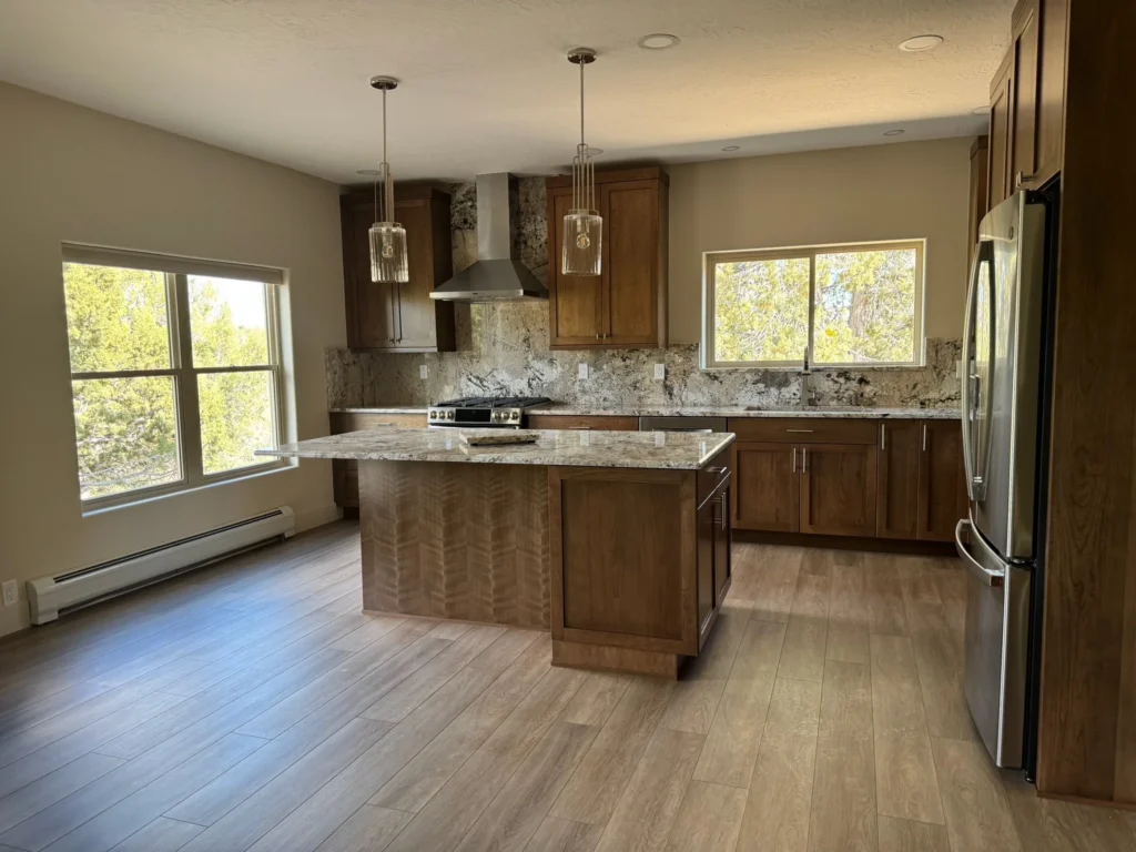 Modern kitchen by Durango Remodeling in Colorado with wood cabinetry, granite countertops, center island, stainless steel appliances, and pendant lighting.